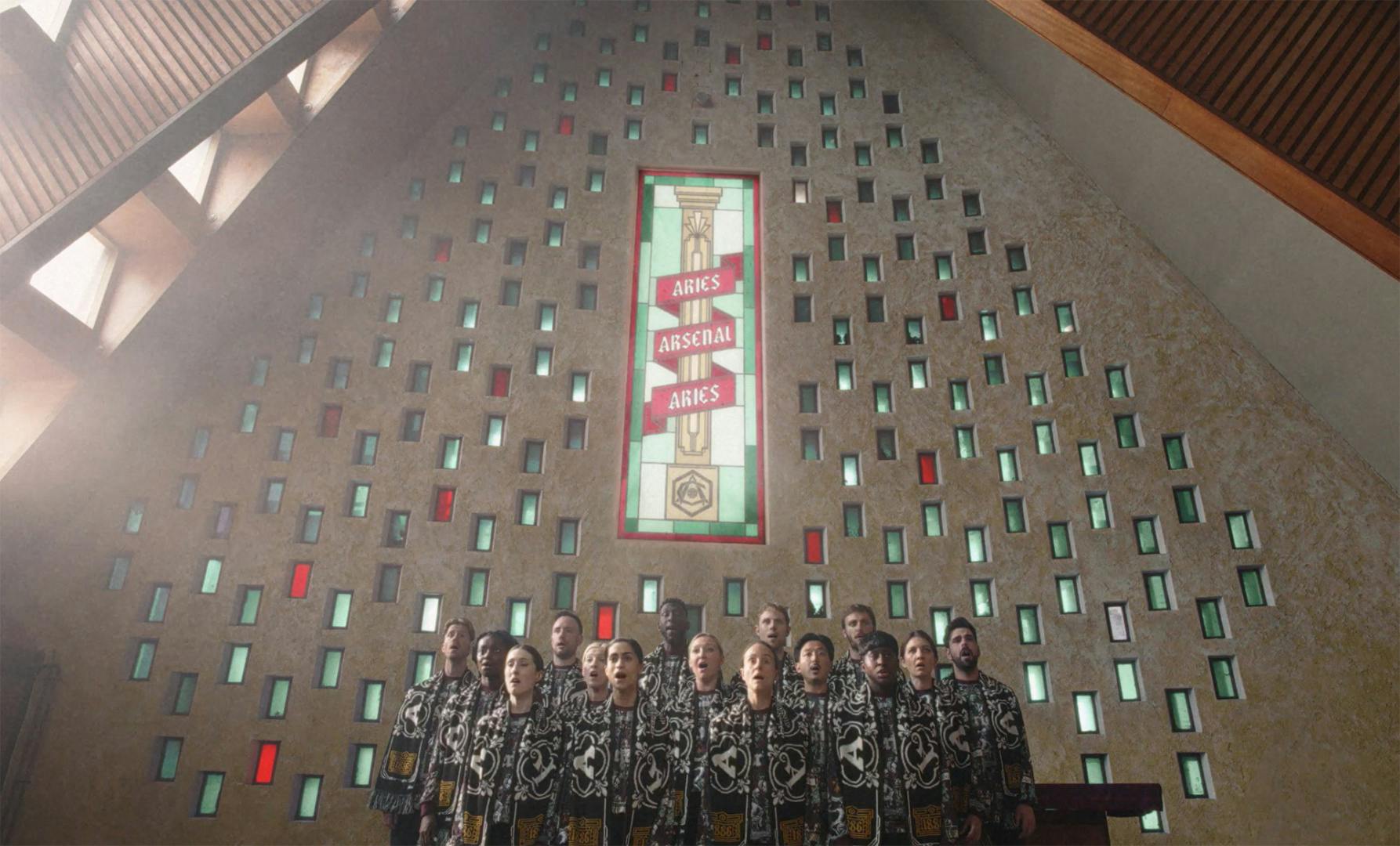 Still from the Aries and Arsenal collaboration campaign film showing a choir standing in a church with an image of a column in the background