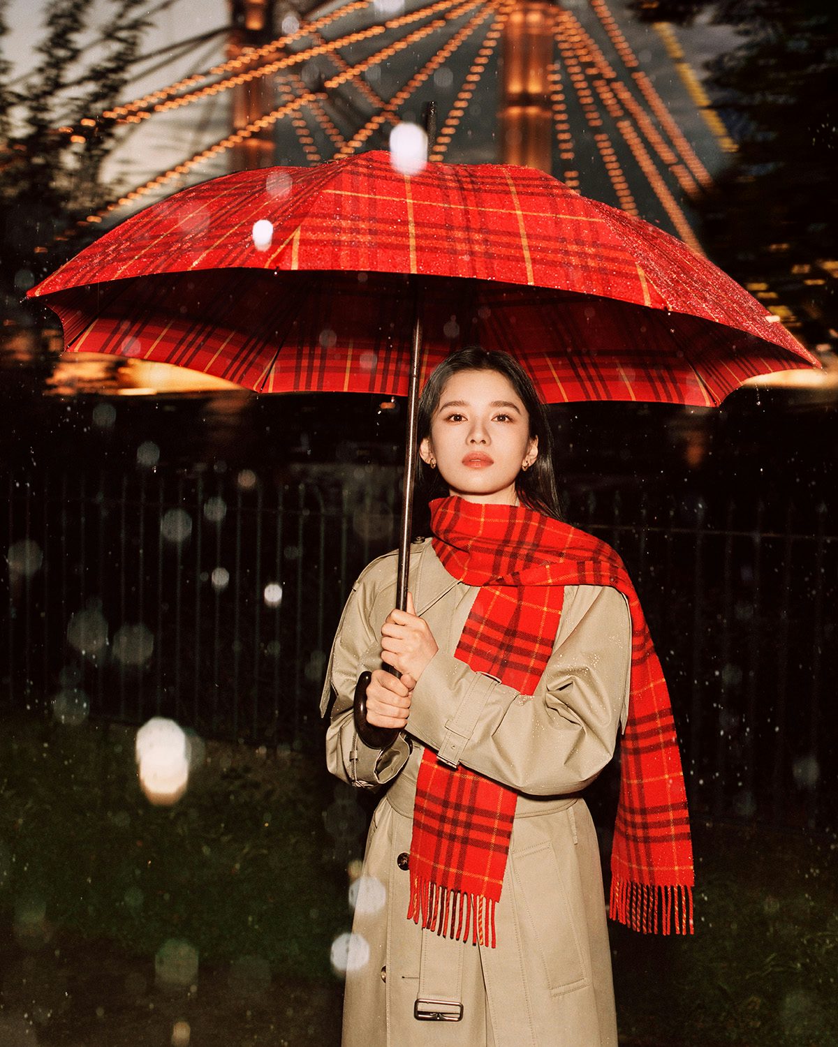Zhang Jingyi wearing a beige Burberry trench, red scarf and a red tartan umberella in the new Burberry outerwear campaign
