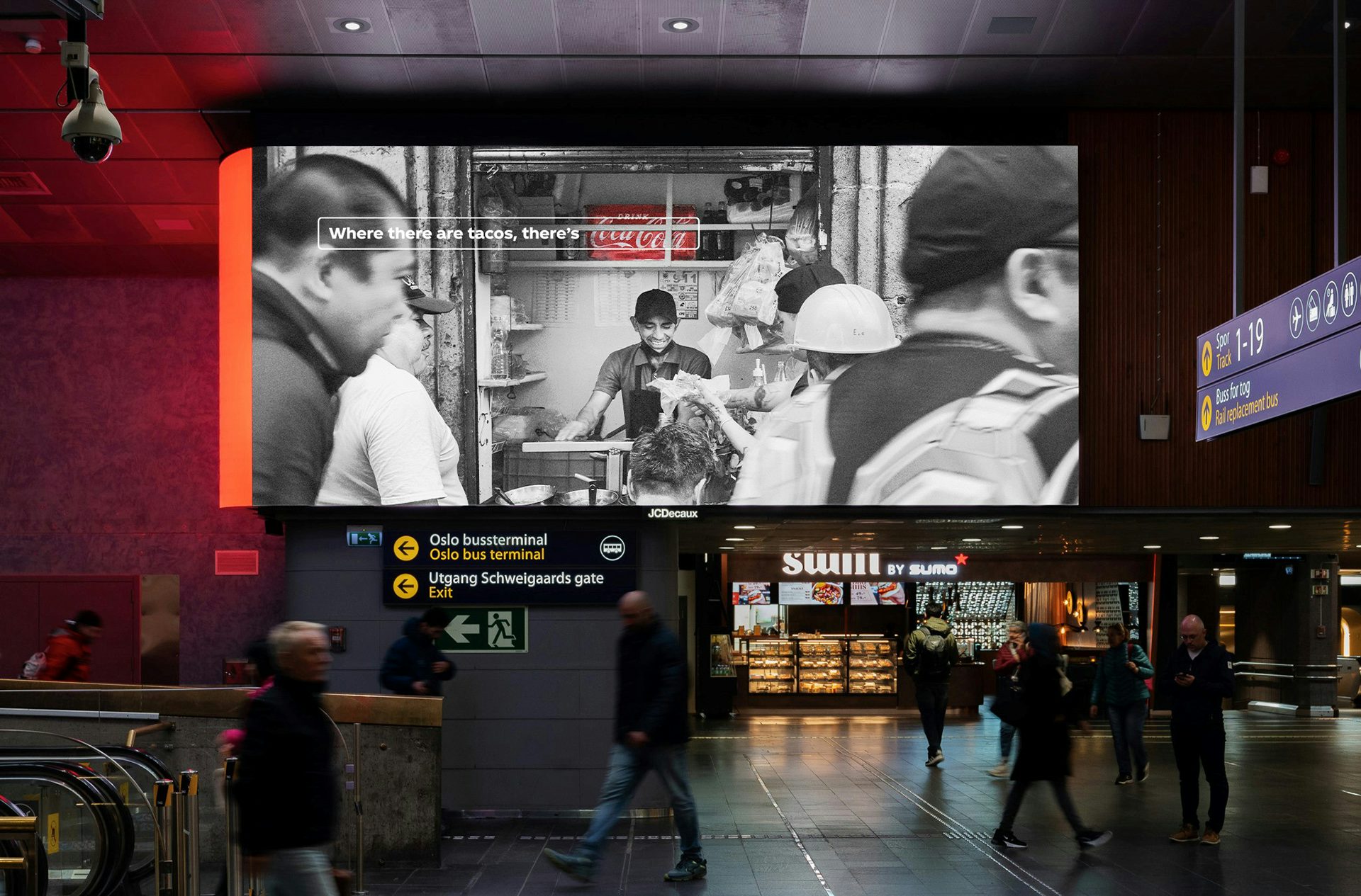 An outdoor ad featuring a black and white photo of a taco stall with a crate of Coca-Cola next to the stall highlighted in red