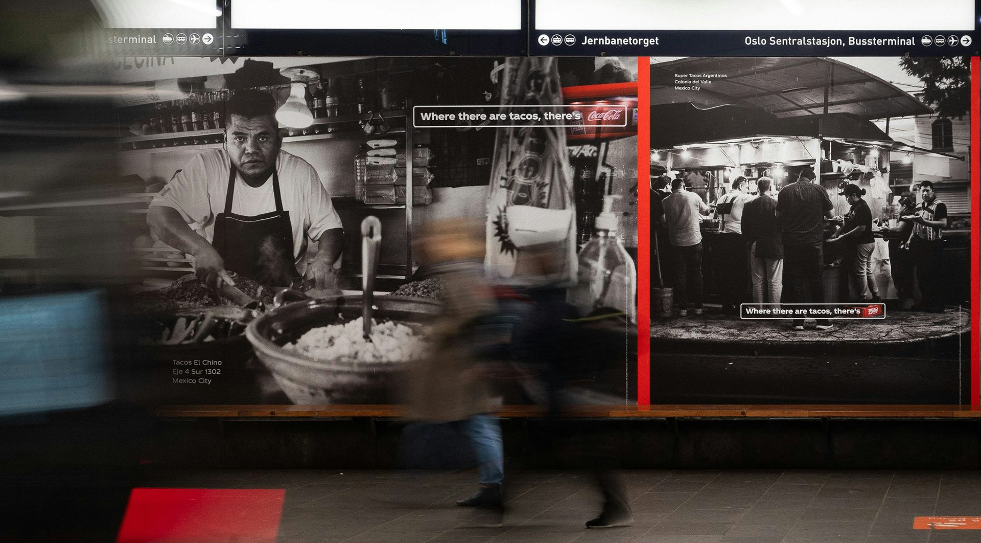 An outdoor ad featuring a black and white photo of a taco stall with a crate of Coca-Cola next to the stall highlighted in red