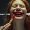 A person eating a chip with ketchup smeared around their mouth, featuring the tagline "It ha ha has to be Heinz"