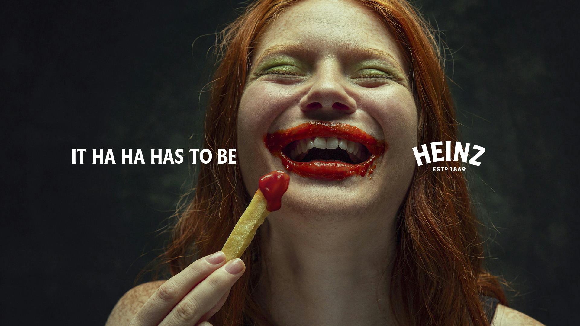 A person eating a chip with ketchup smeared around their mouth, featuring the tagline "It ha ha has to be Heinz"