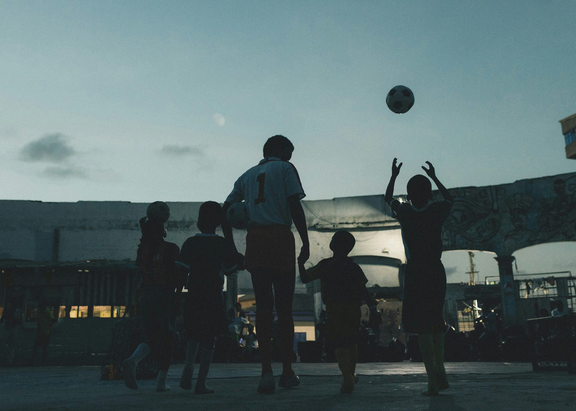 Photo by Carlos Idun-Tawiah showing people playing basketball outside at dusk
