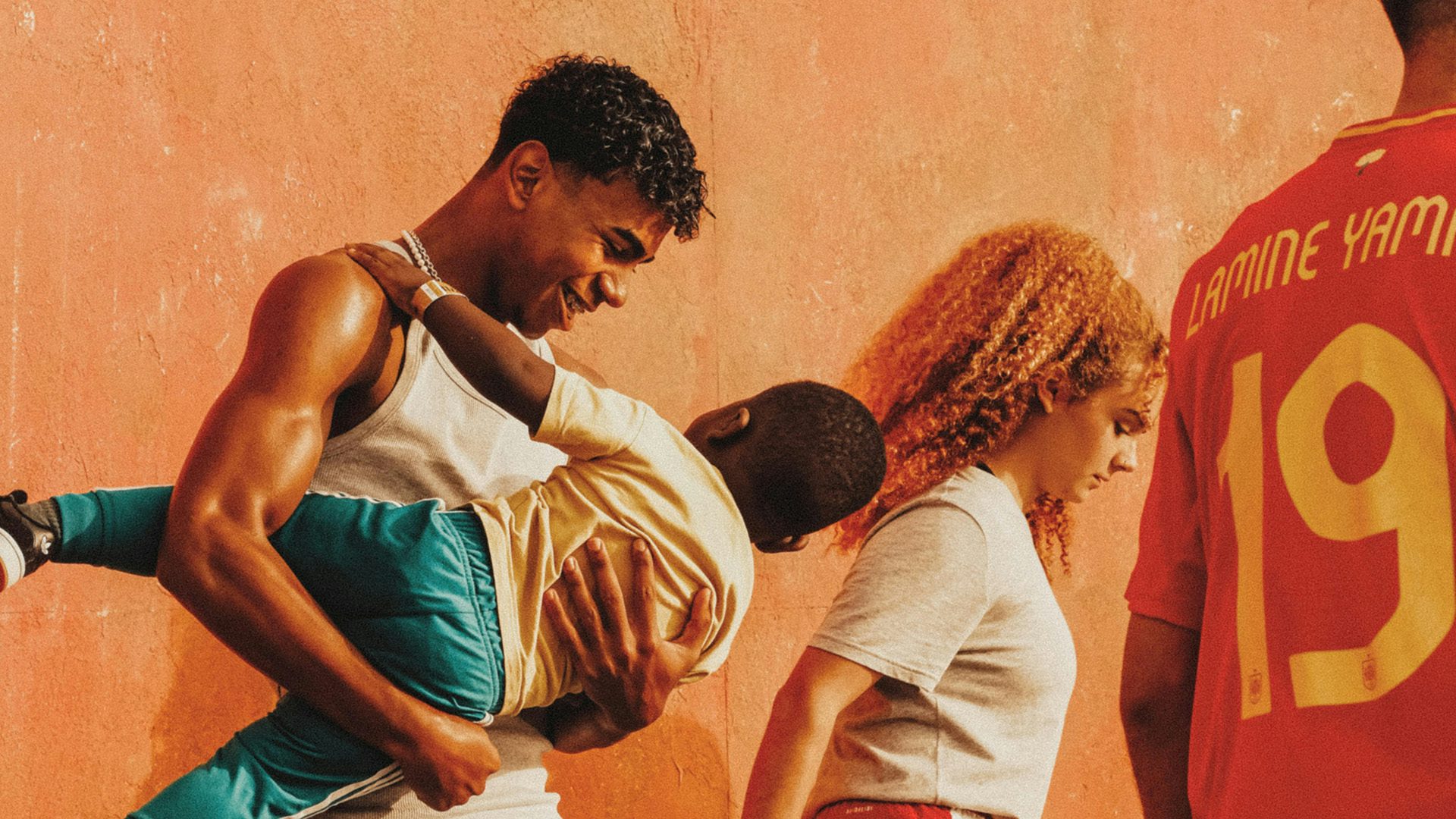 Still from adidas campaign showing footballer Lamine Yamal smiling while cradling a child