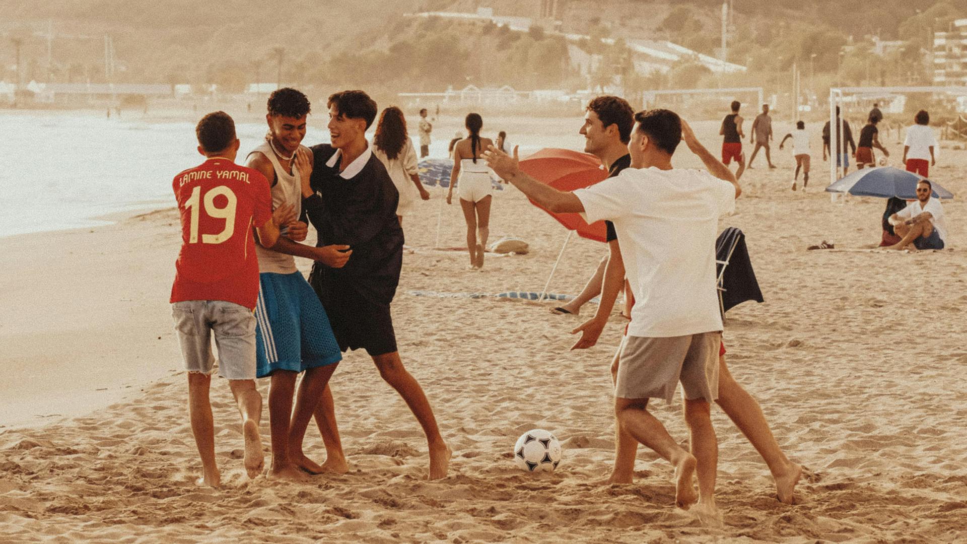 Still from adidas campaign showing footballer Lamine Yamal playing football on a beach with other young people