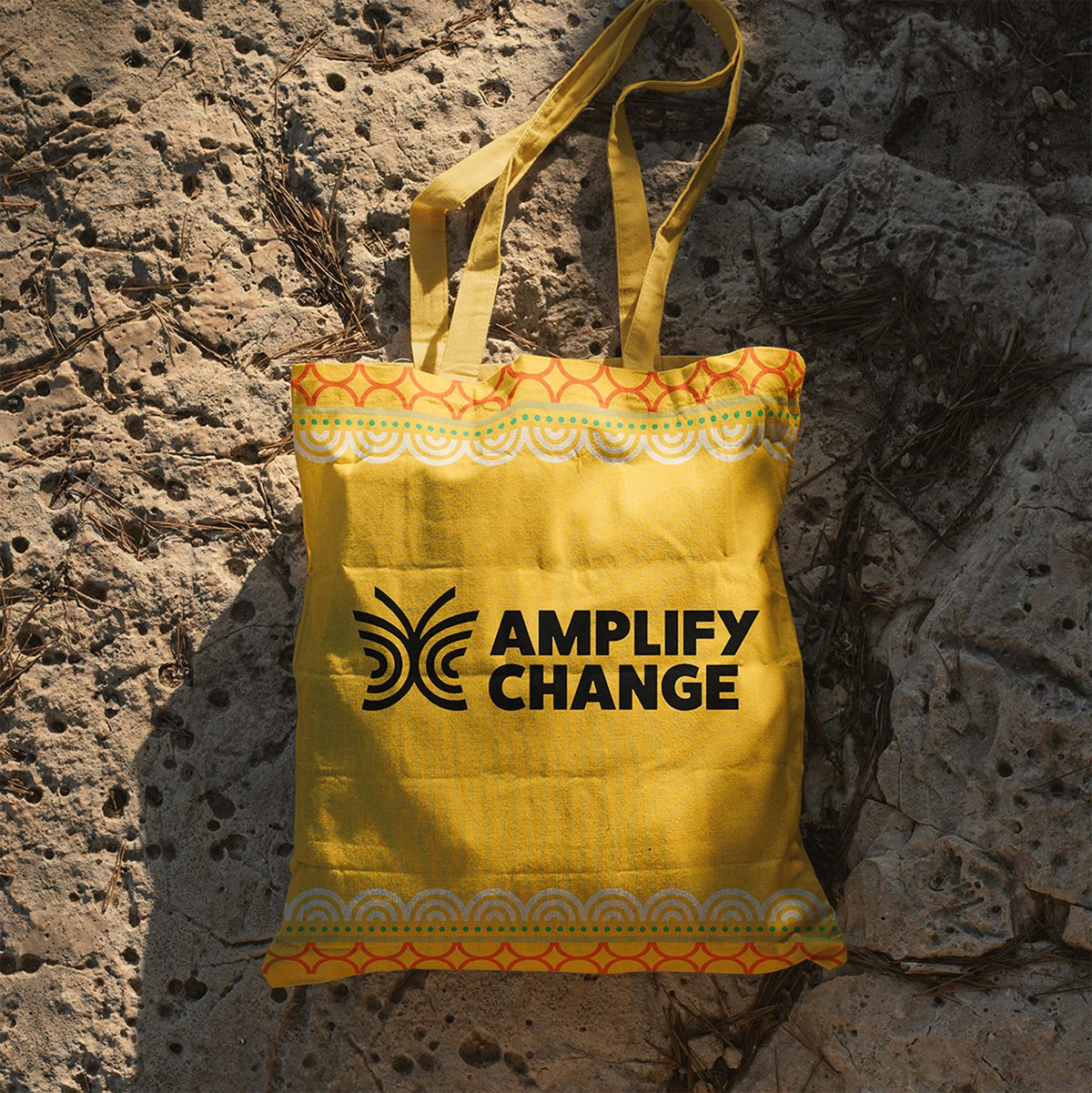 Yellow tote bag labelled 'Amplify Change' and a butterfly symbol