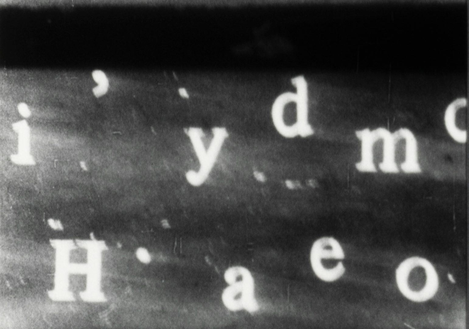 Film still featuring letters arranged sparsely on a faded black background, taken from Mubi's book Read Frame Type Film