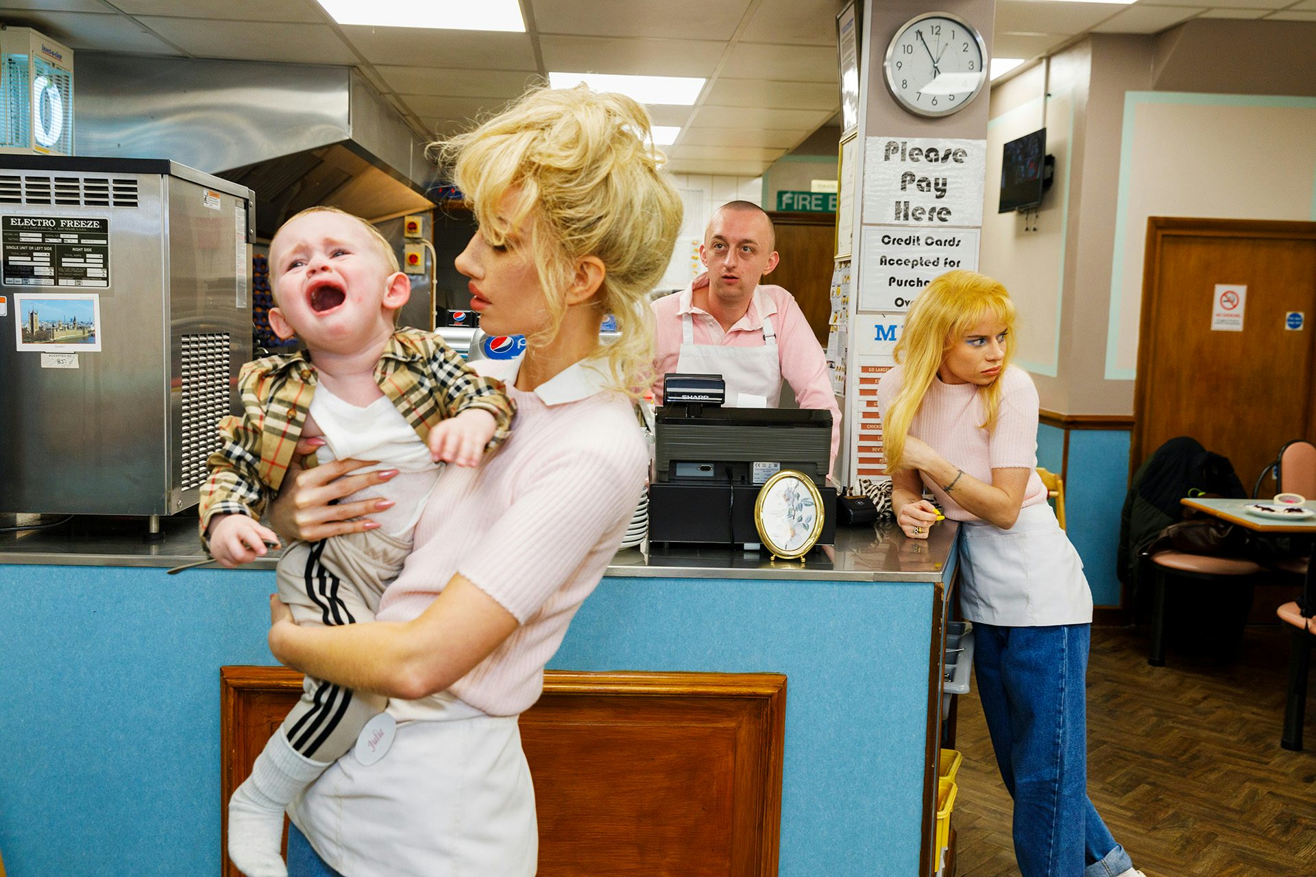 Photo from Julie Bullard by Nadia Lee Cohen and Martin Parr of a blonde woman holding a screaming child in a cafe