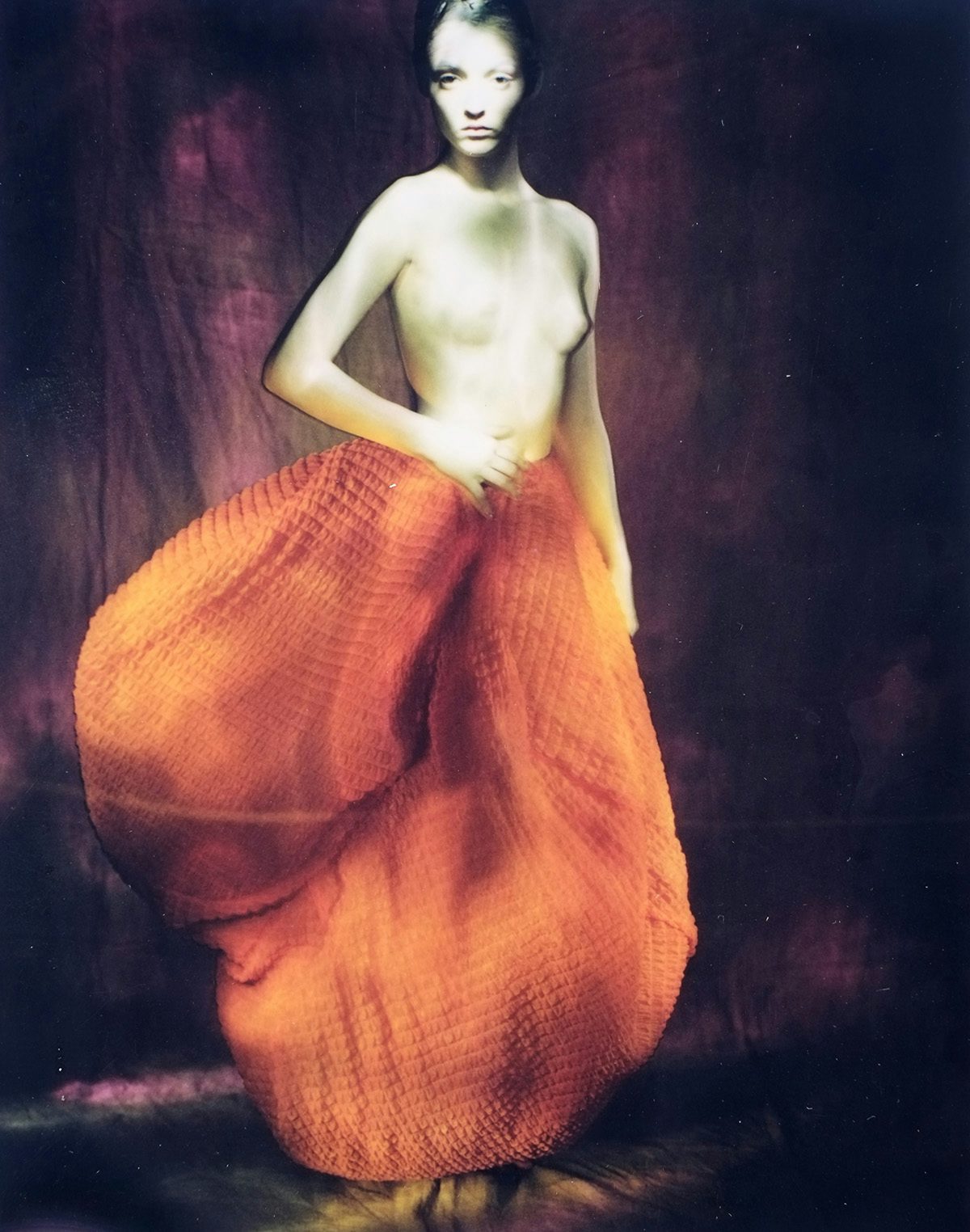Blurred image by Paolo Roversi of a topless model wearing a ballooned orange skirt
