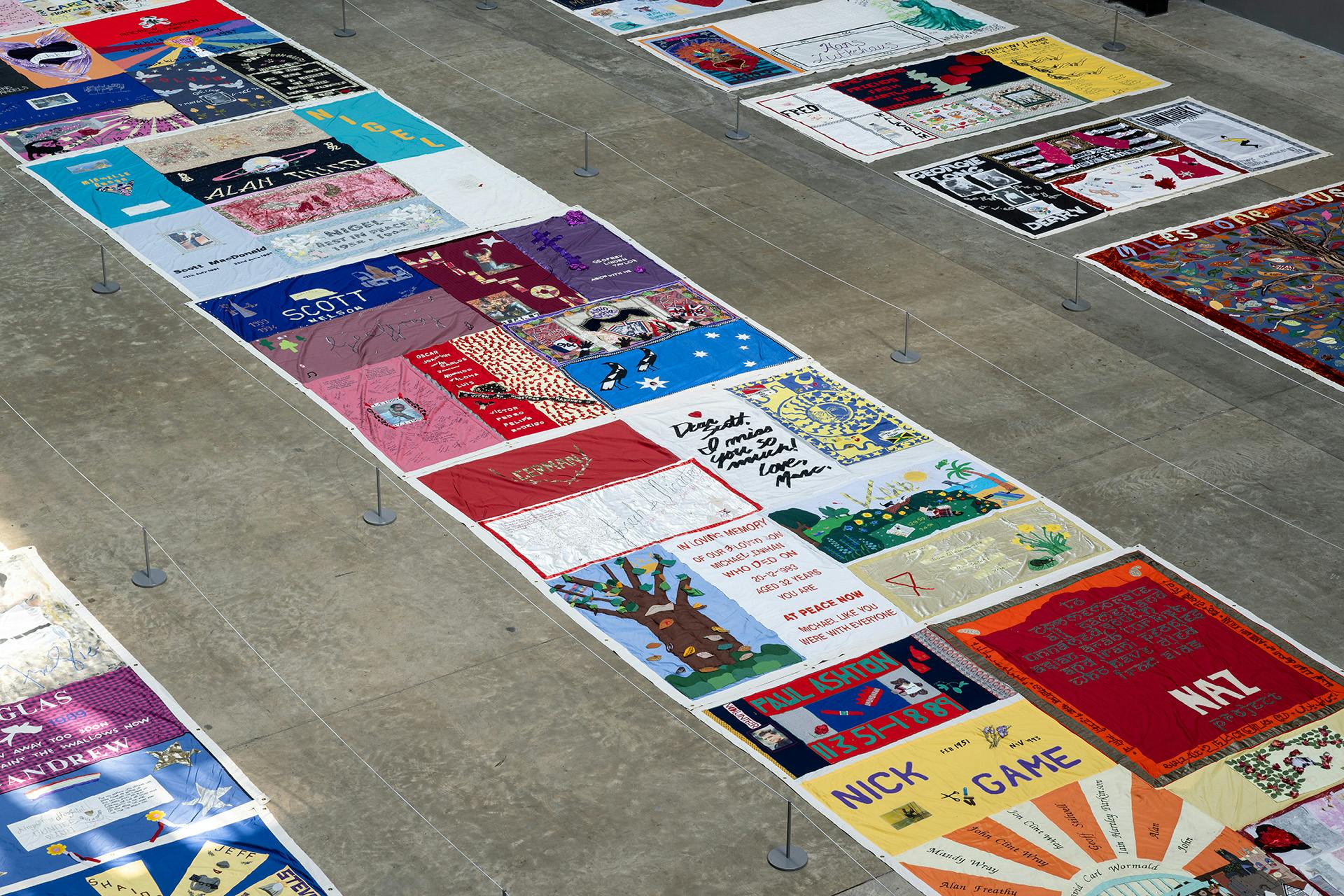 UK AIDS Memorial Quilt laid out in three long rows in Tate Modern's Turbine Hall