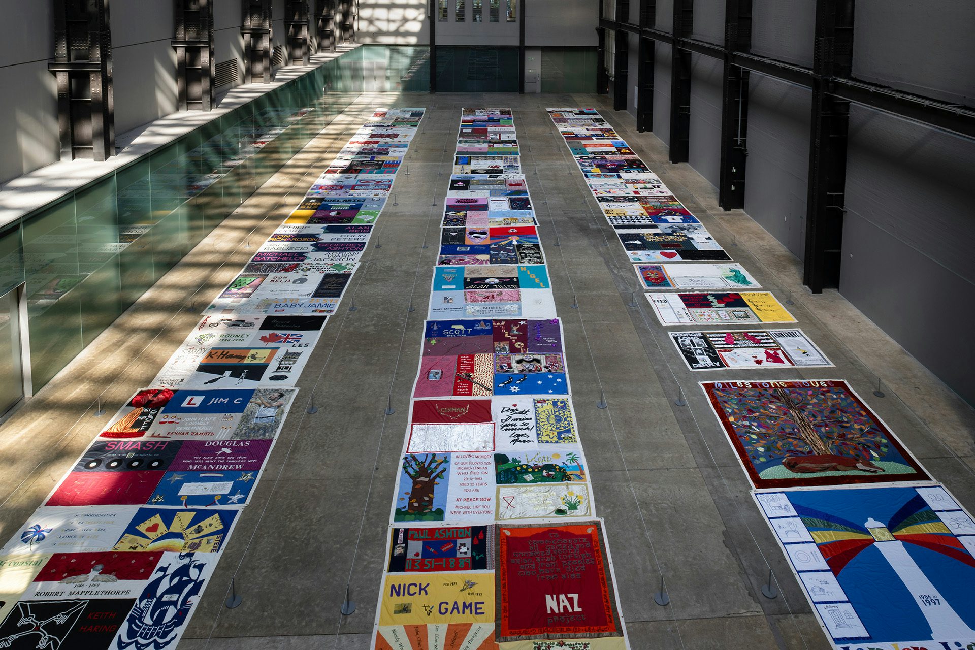 UK AIDS Memorial Quilt laid out in three long rows in Tate Modern's Turbine Hall