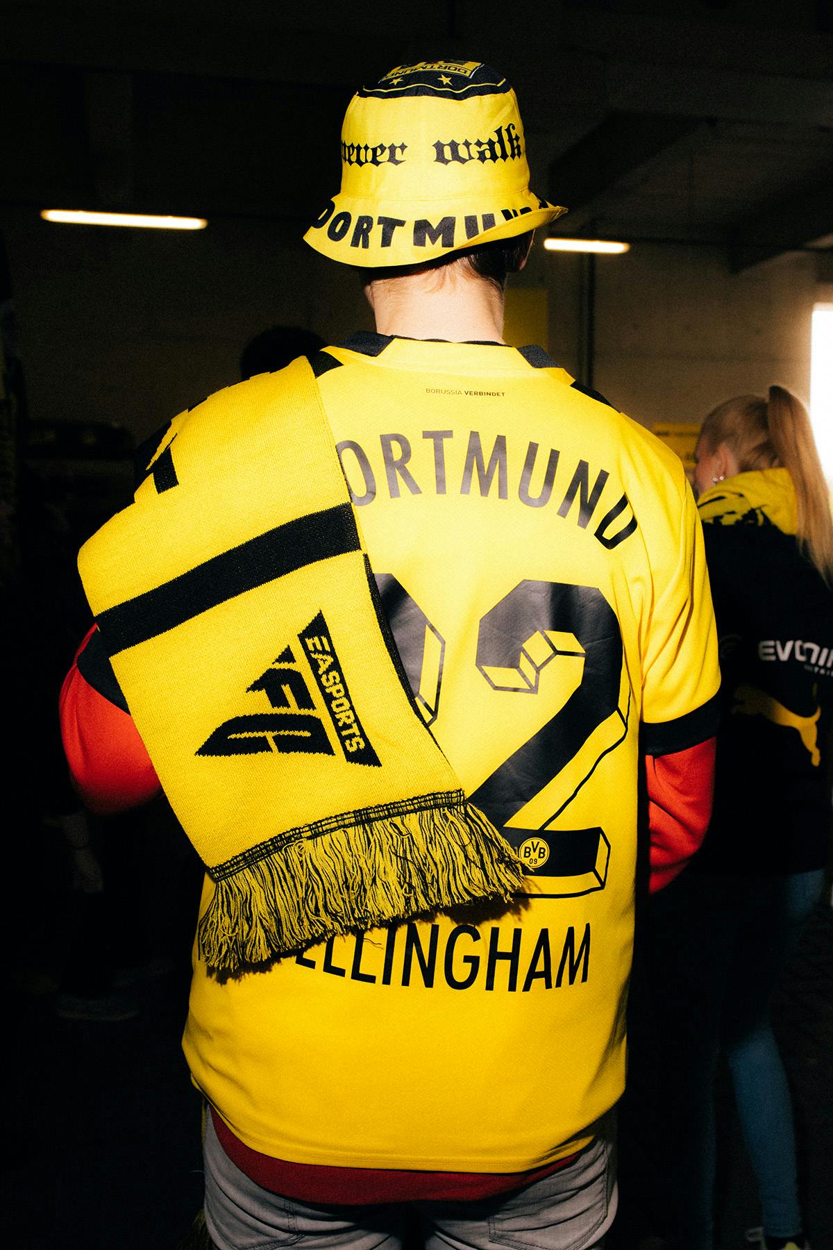 Image showing the new sloping EA Sports FC logo on a yellow scarf, being worn by someone wearing a yellow Dortmund football shirt
