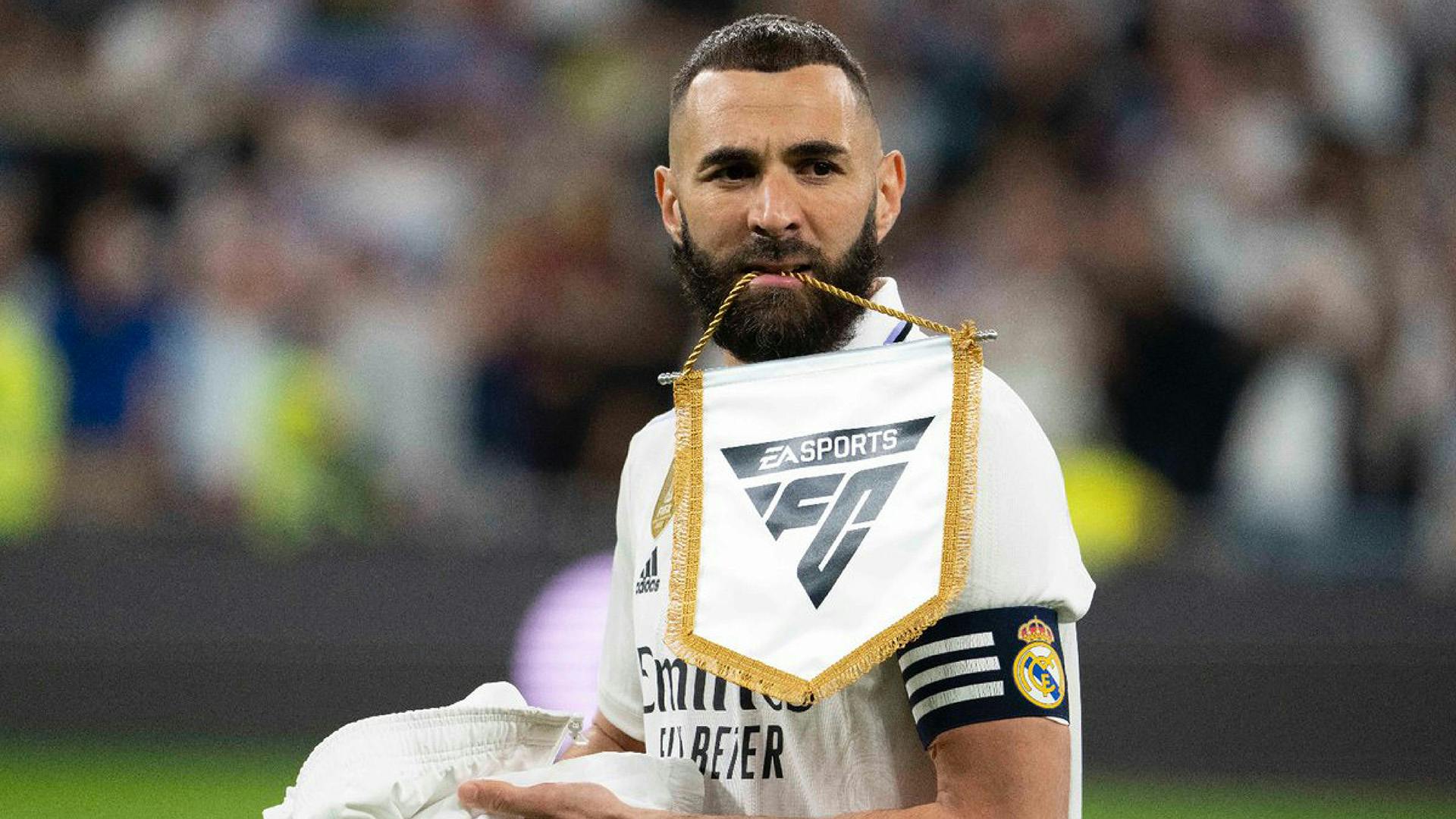 Image showing footballer Karim Benzema holding a flag in hiis mouth featuring the new sloping EA Sports FC logo
