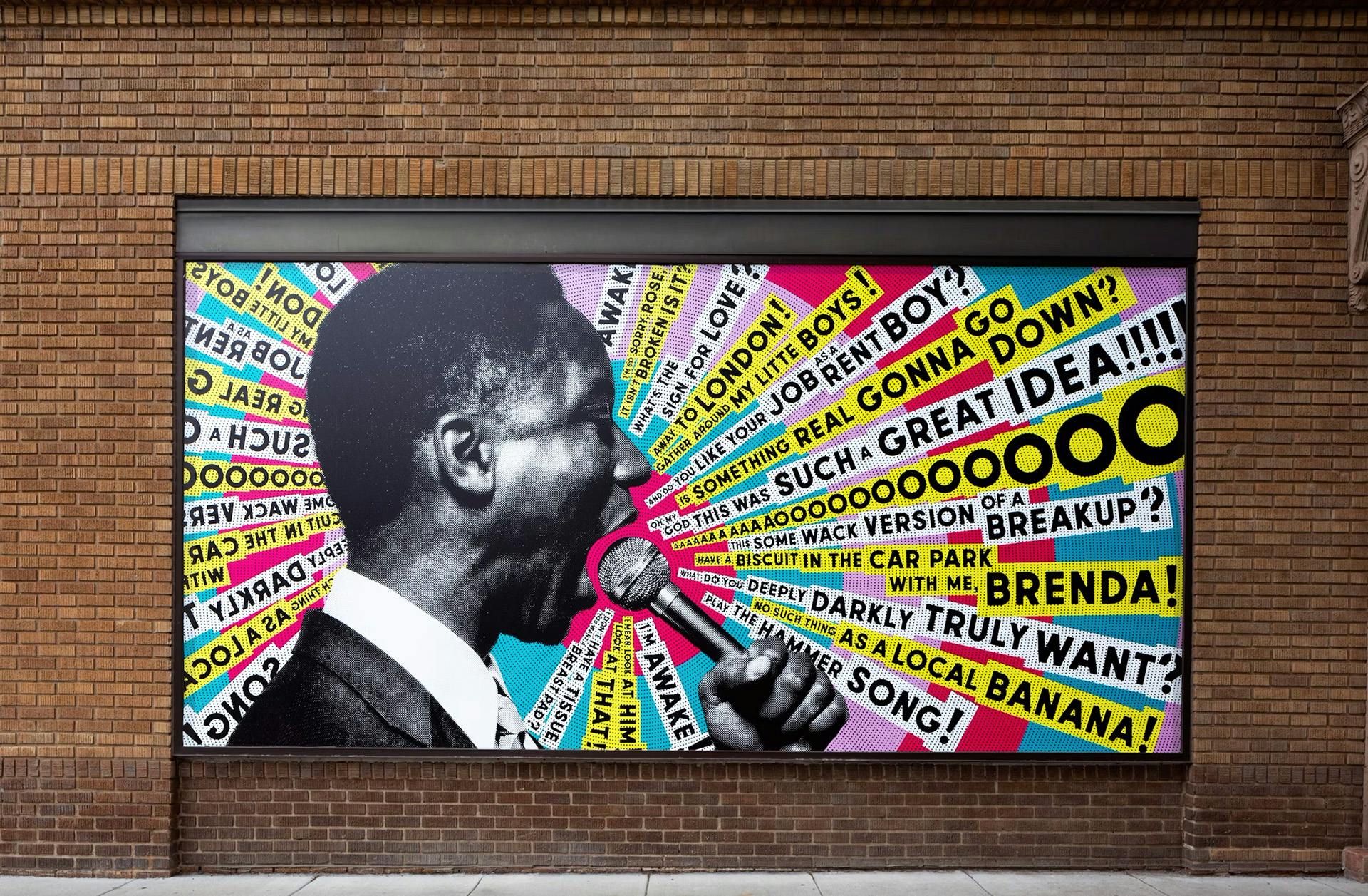 Studio Theatre poster displayed on a brick wall featuring a black and white photo of a person speaking into a microphone with colourful lines of text radiating out from the microphone