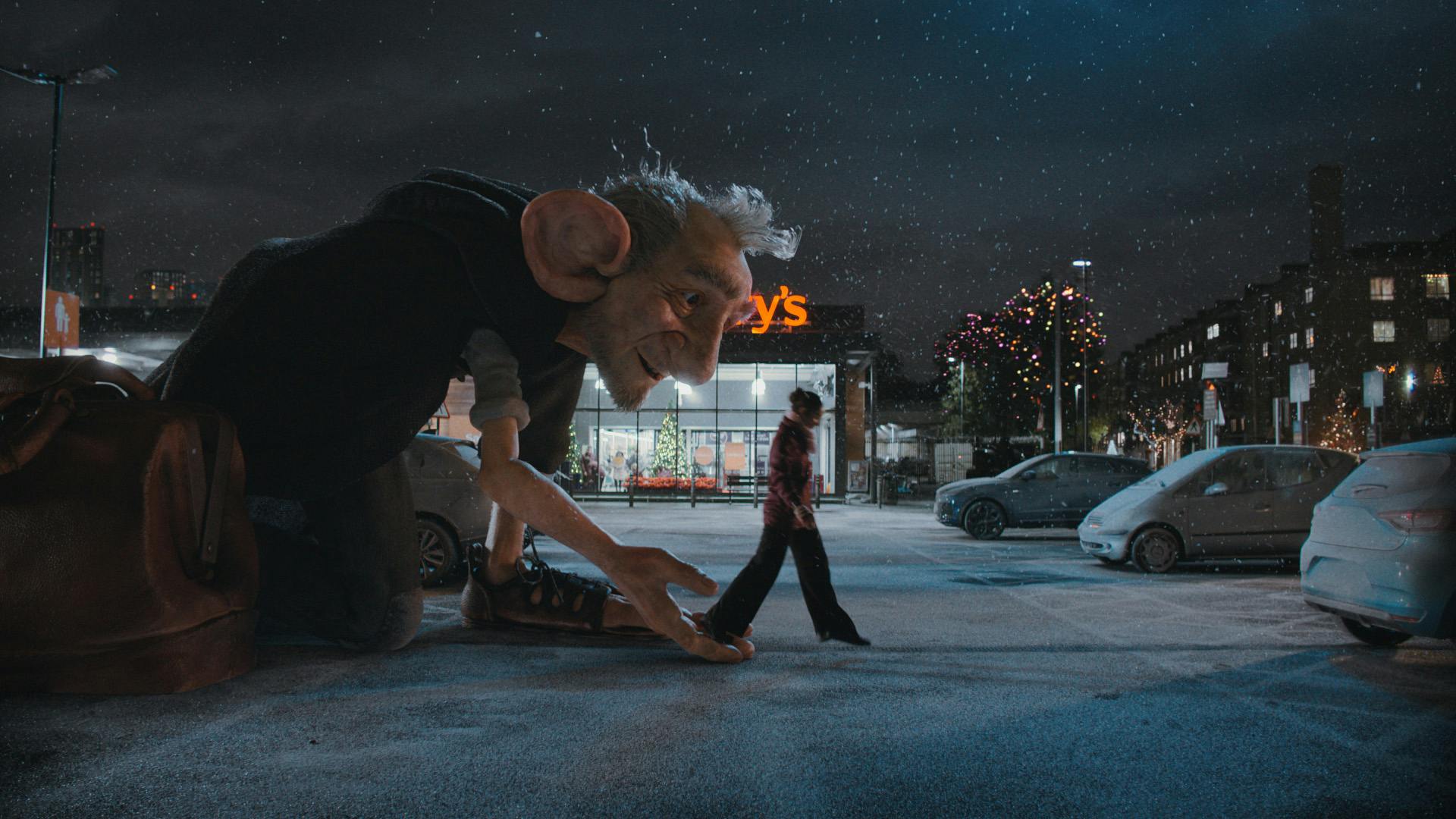 The BFG crouching down next to a person outside a snowy Sainsbury's carpark