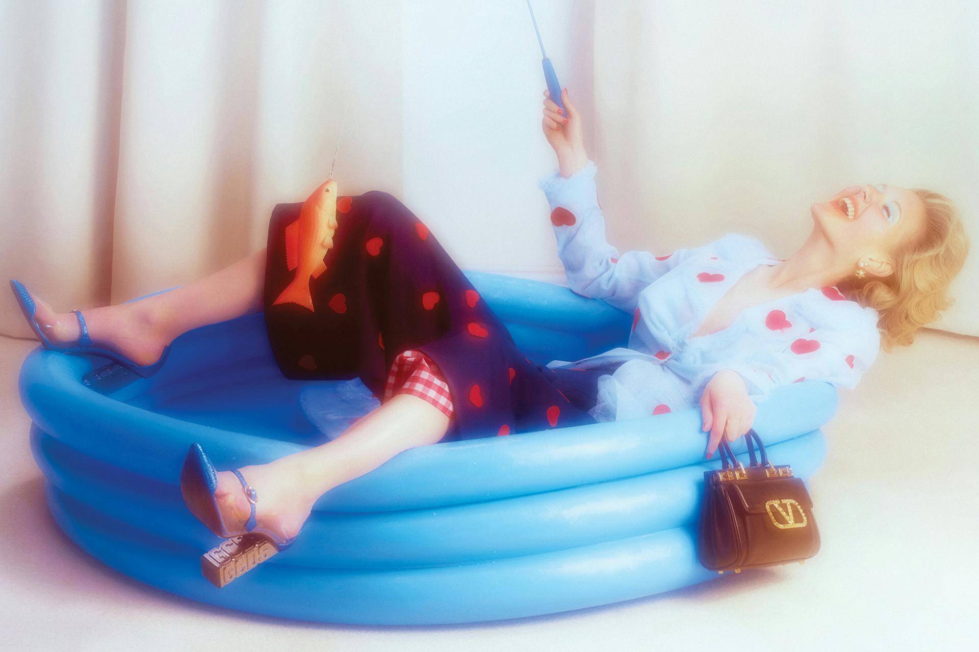 Photo by Jakub Gessler of a person wearing glam clothing and leaning back in a blue paddling pool