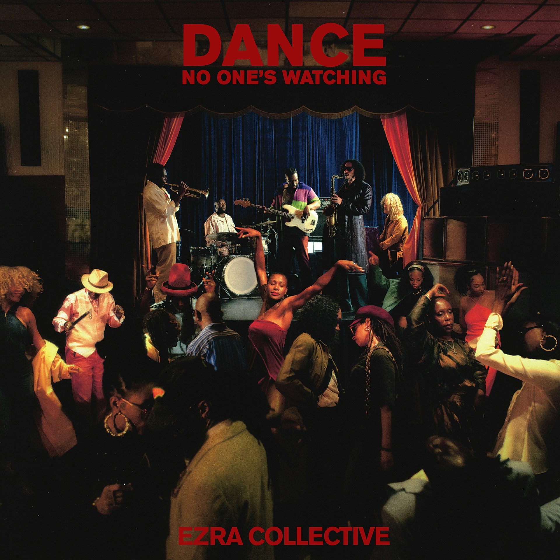 Album art for Dance No Ones Watching by Ezra Collective featuring a crowd dancing in a darkened room in front of the band on stage