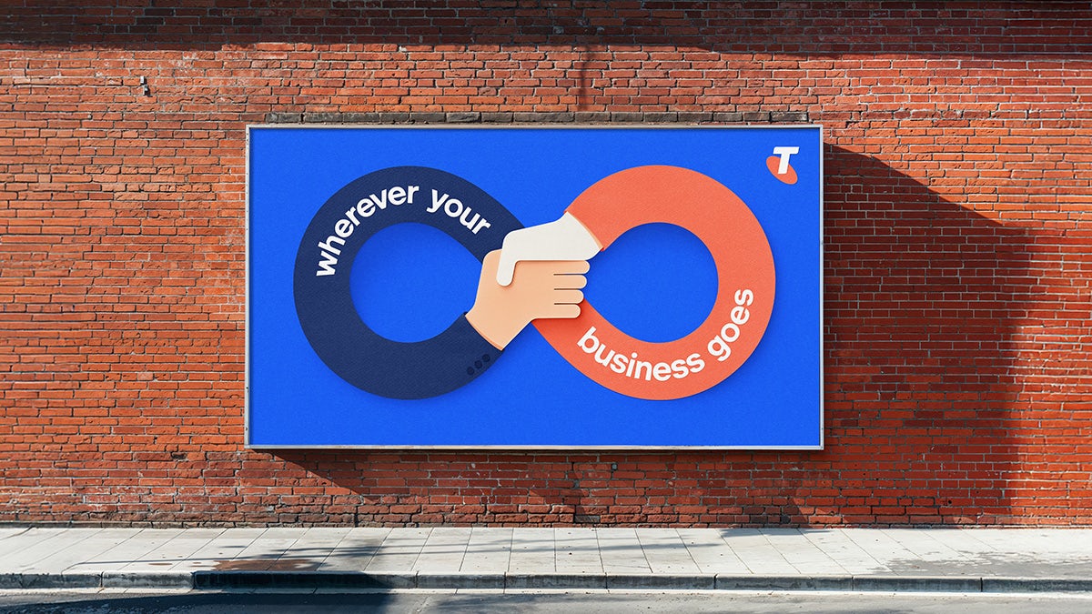 Outdoor billboard for Telstra Business featuring an illustration of two arms interlinked in an infinity shape and the tagline 'wherever your business goes'