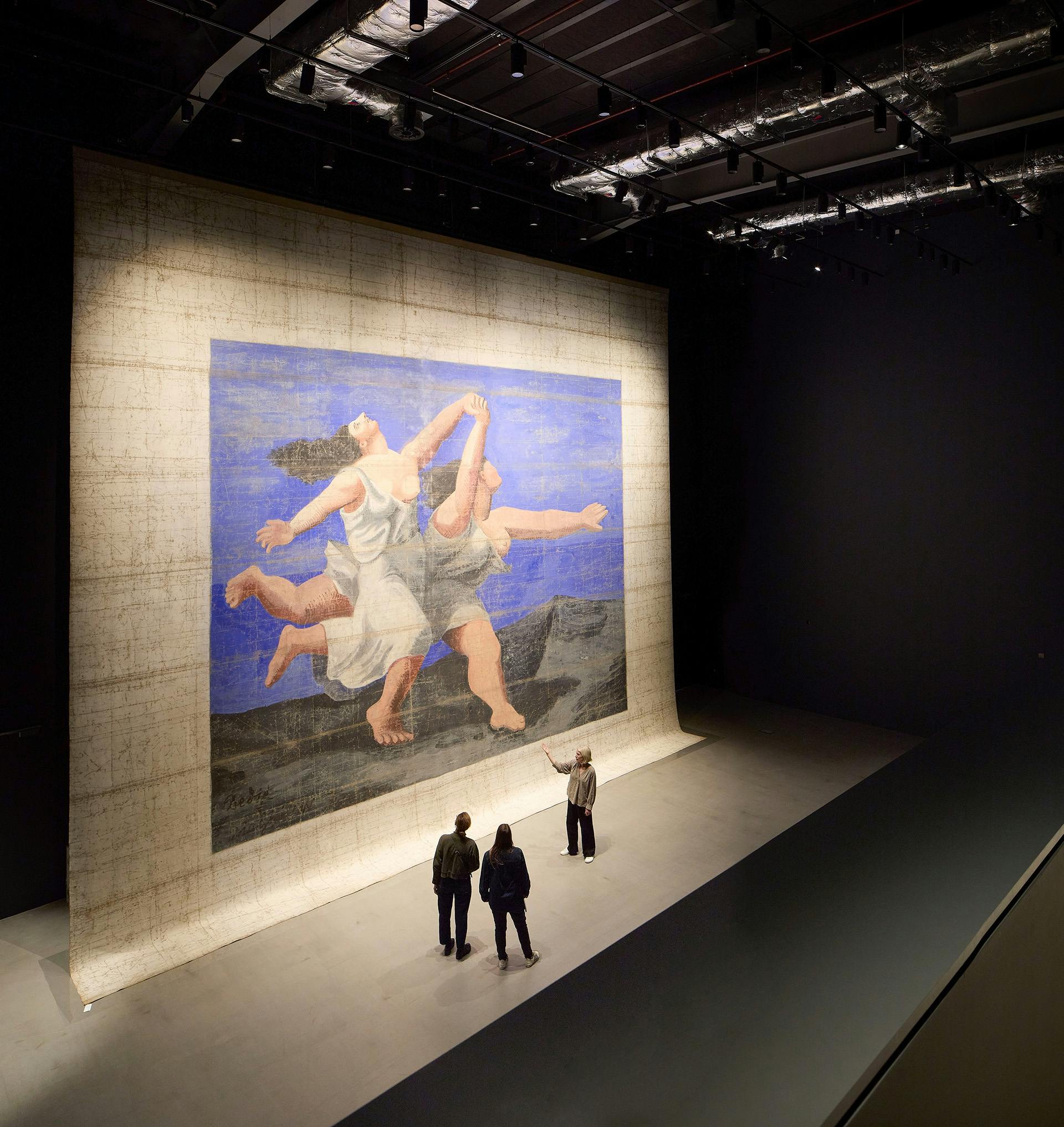 Ten-metre tall stage backdrop showing two dancers displayed inside a large darkened room at the V&A East Storehouse