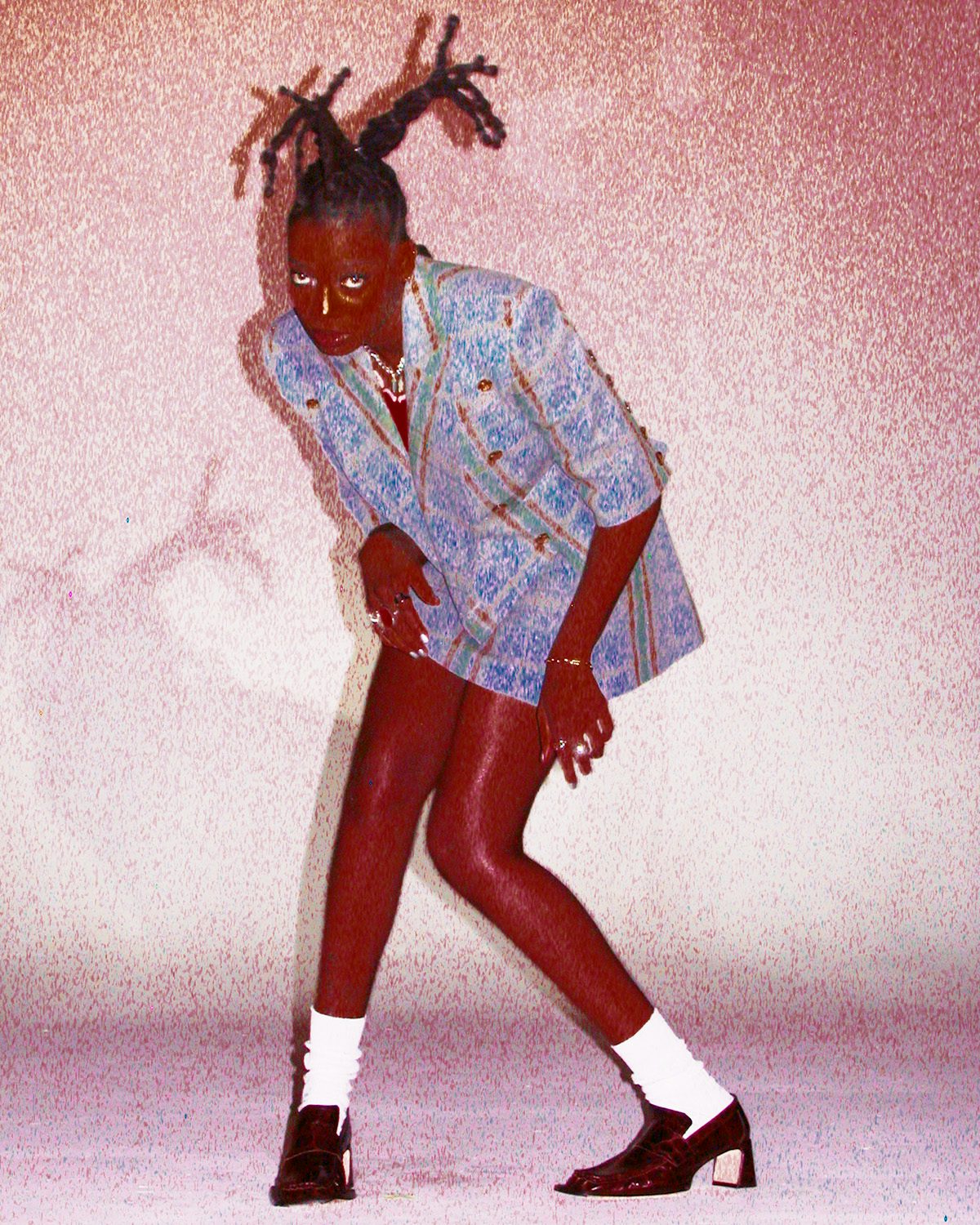 Oversaturated photo of Little Simz weather a thigh-length check jacket, white socks and heeled loafers by Thibaut Grevet