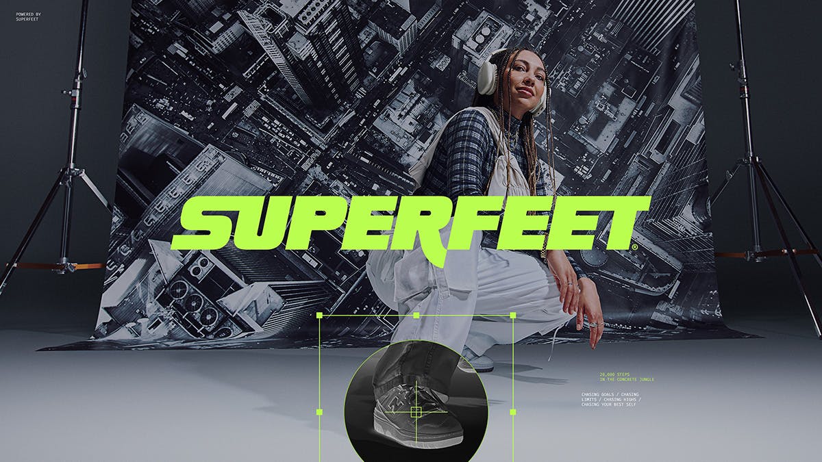 A person wearing shoes featuring an overlaid graphic showing the sole technology, and a bright green Superfeet wordmark over the top