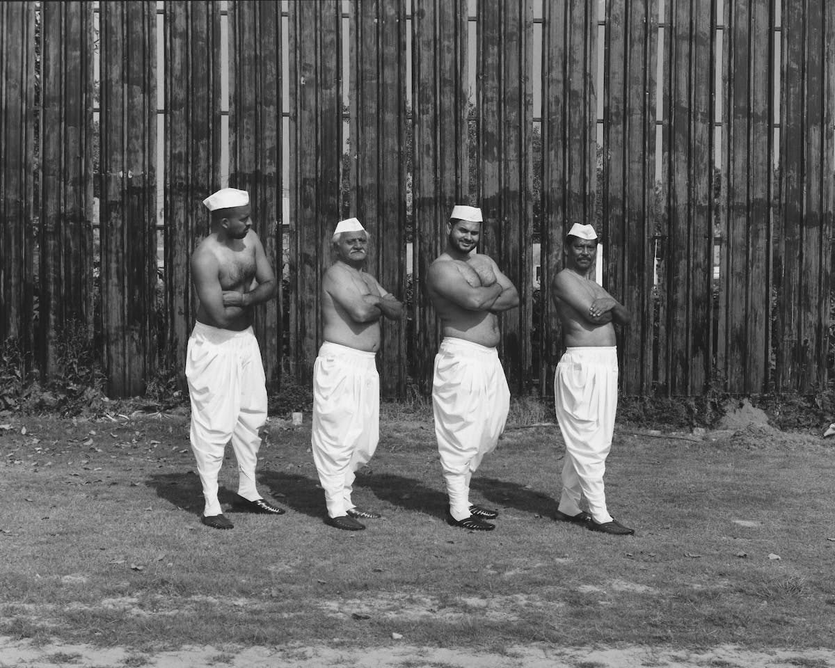 Black and white photo by Vivek Vadoliya featuring four men in a row wearing headdress and bare torsoes