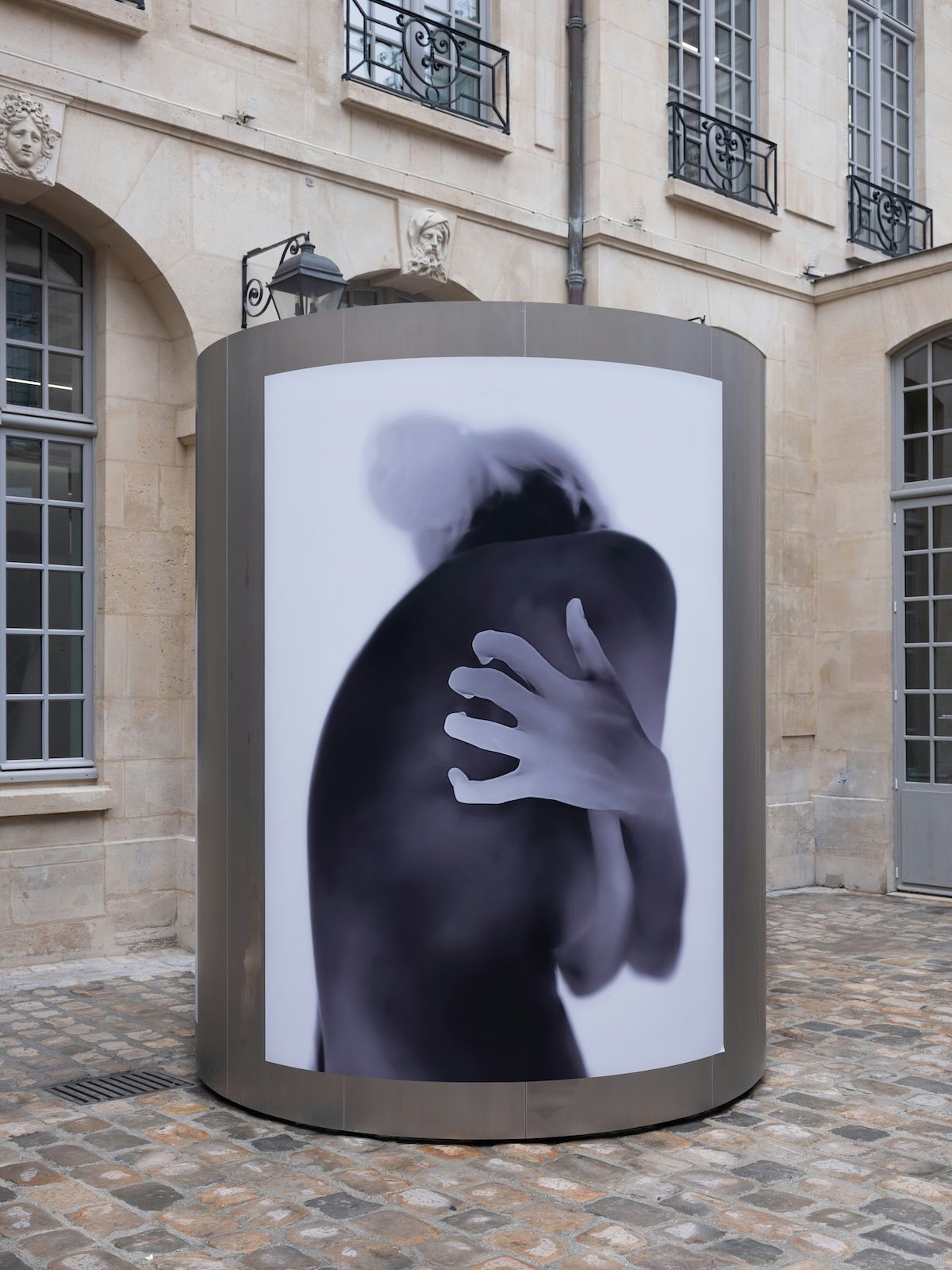 Thermal image of a person contorting their arms and bare back by Yulia Mahr displayed on a pillar outside Dover Street Market Paris