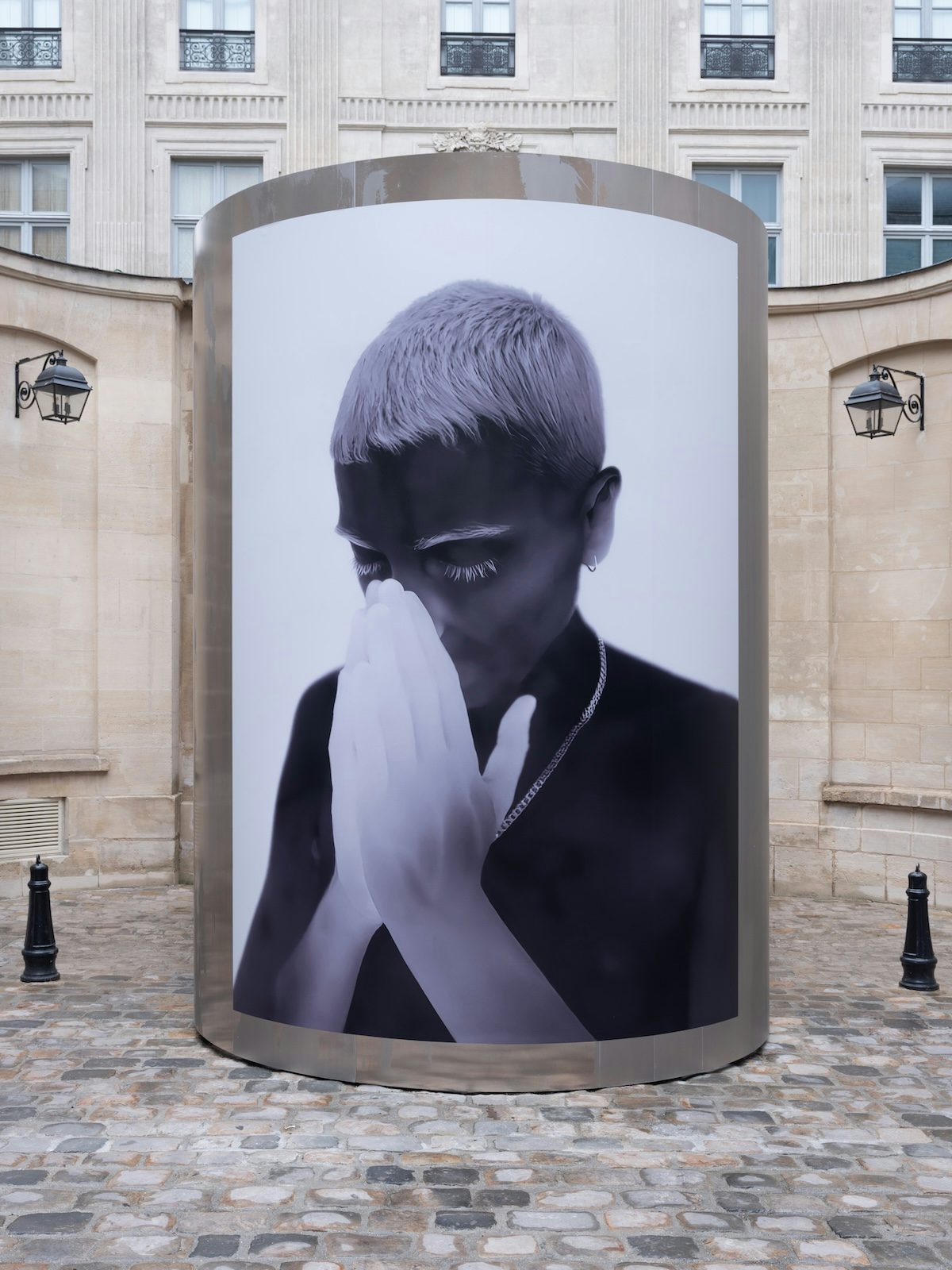 Thermal image of a person cupping their own face by Yulia Mahr displayed on a pillar outside Dover Street Market Paris
